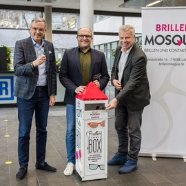 Dr. Jochen Weyrauch (links), Oberbürgermeister Jürgen Kessing (rechts) und Brillen-Mosqua-Geschäftsführer Markus Stammberger (Mitte) bei der Übergabe der Brillenspende